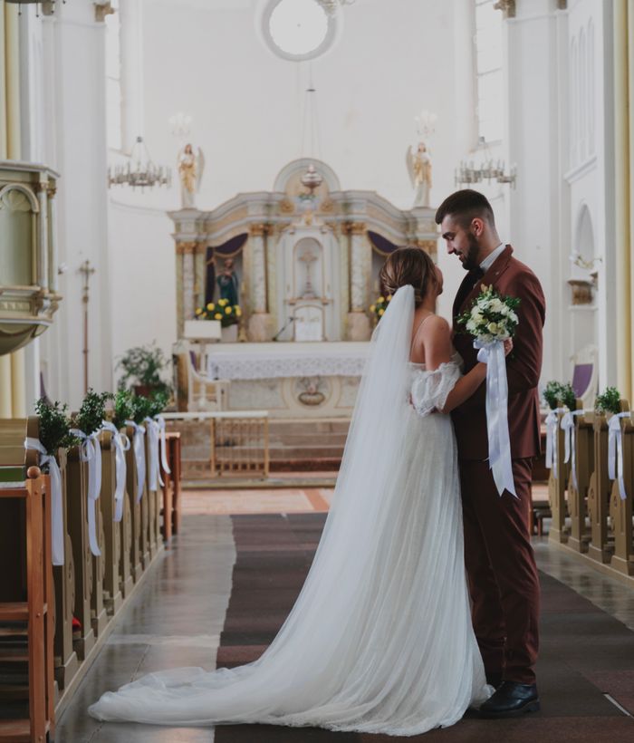 Une magnifique cérémonie de mariage dans une grande cathédrale, avec la mariée et le marié enlacés.